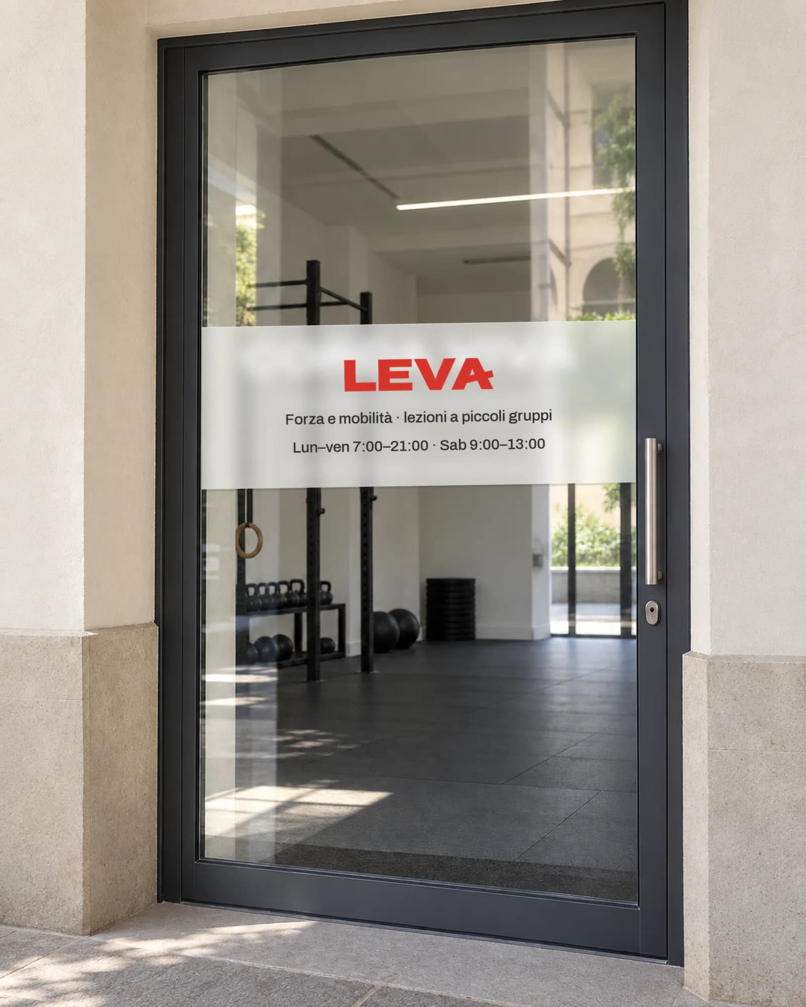 Porta a vetri dello studio con una fascia satinata: il logotipo Leva in rosso, sotto la descrizione e gli orari